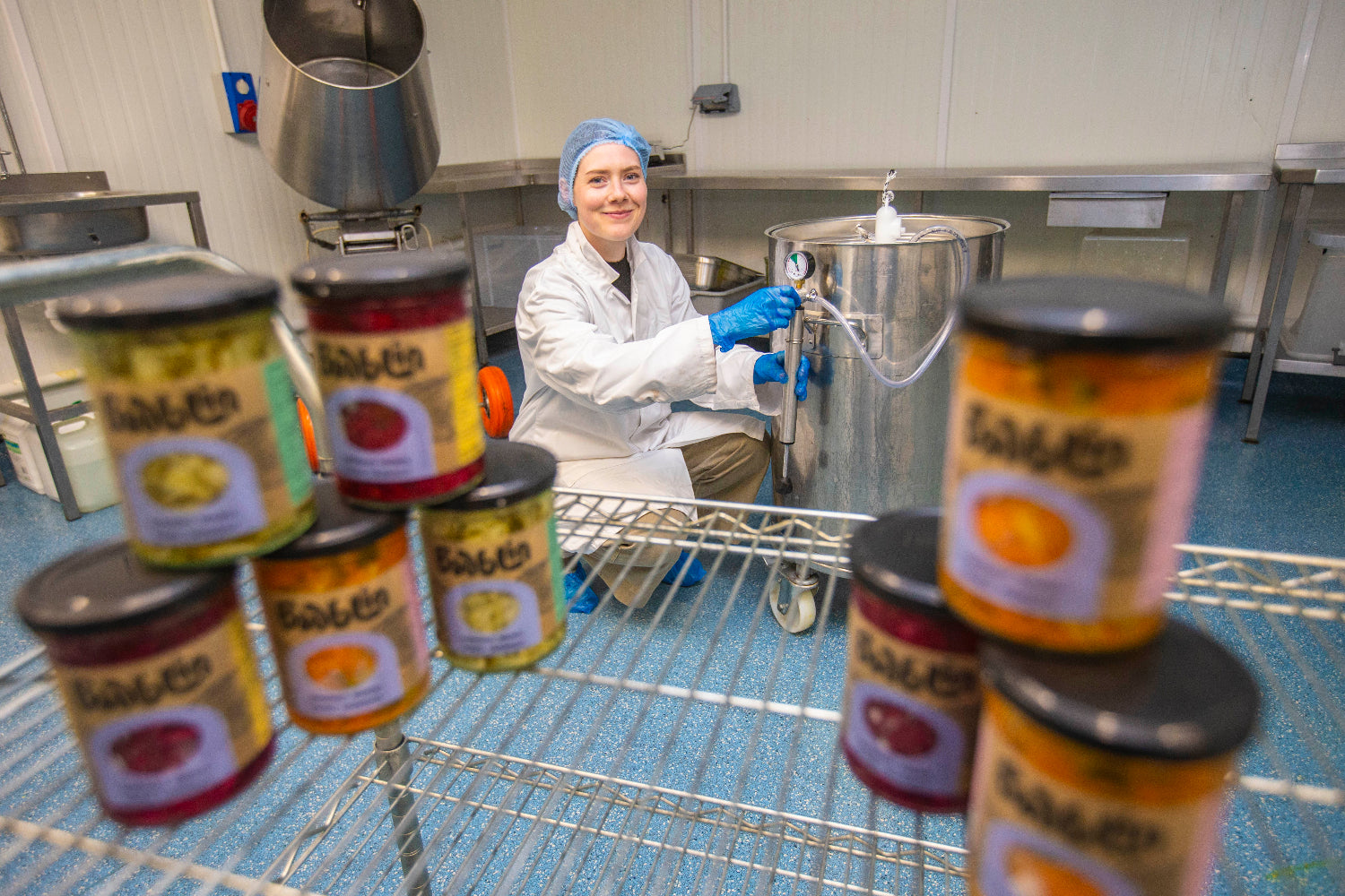 Person in a food processing facility with jars fermented food