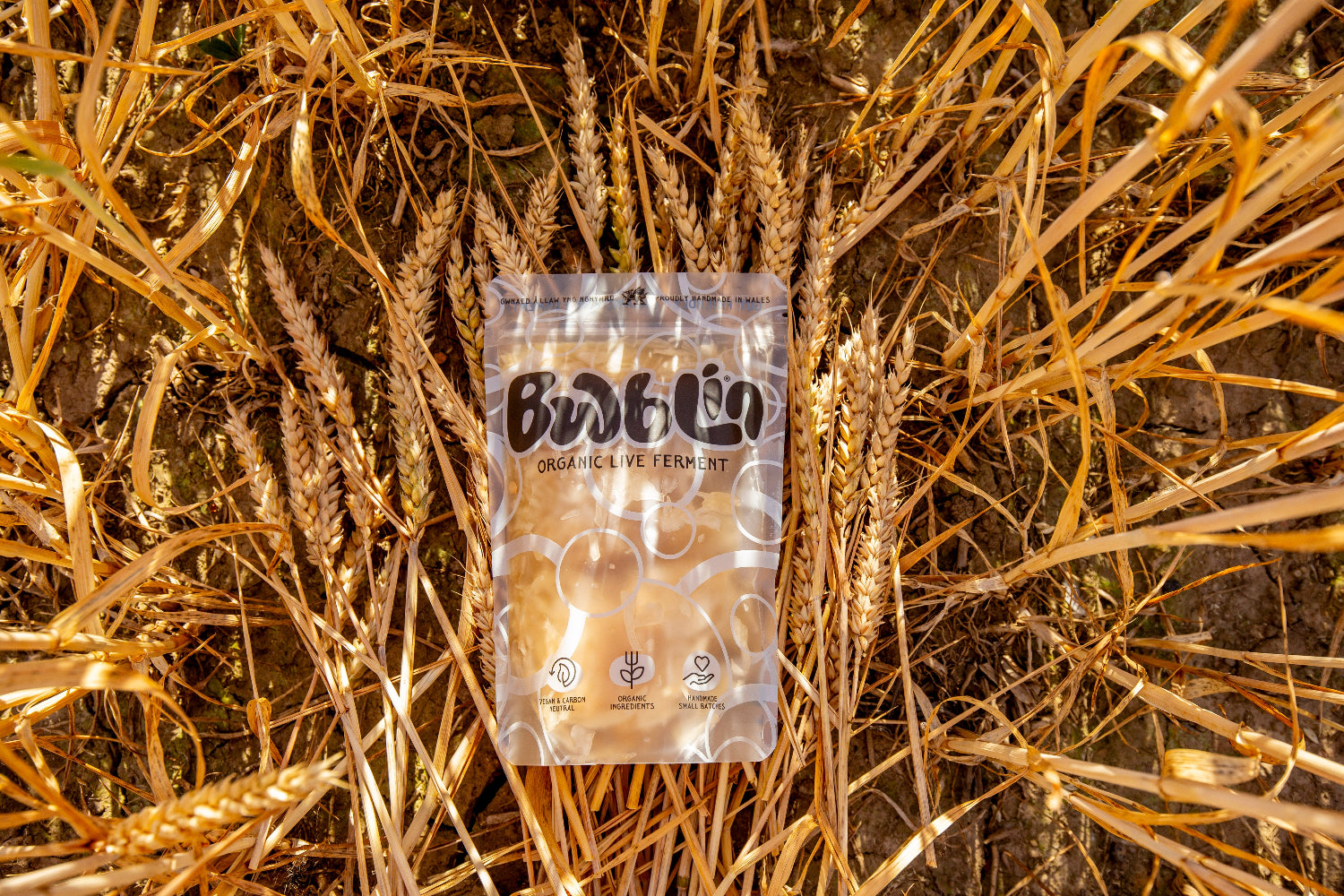 A clear plastic pouch of Bwblin Organics Veterinary Diet placed on a bed of golden wheat stalks.