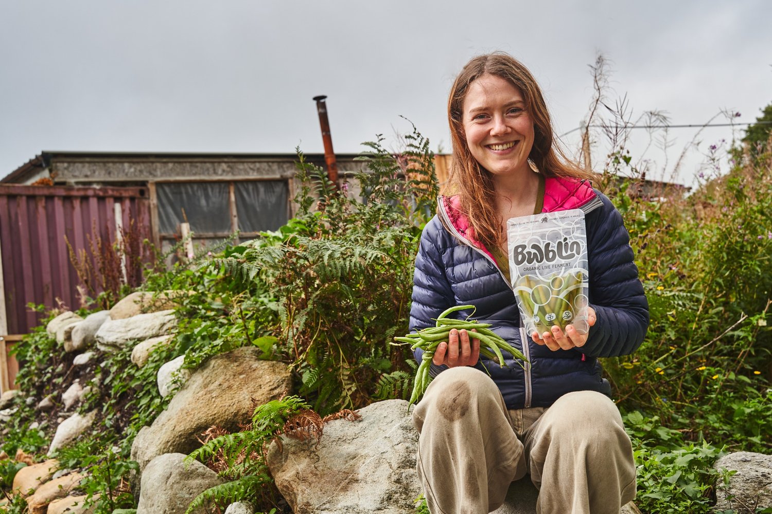 Person holding a bag of seeds in a garden setting