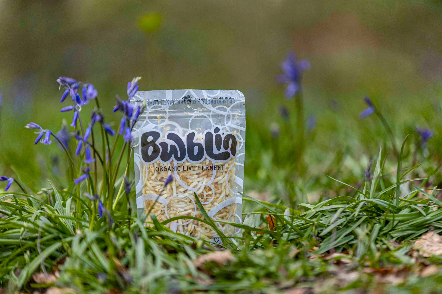 Package of Bwblin organic live ferment on grass with purple flowers
