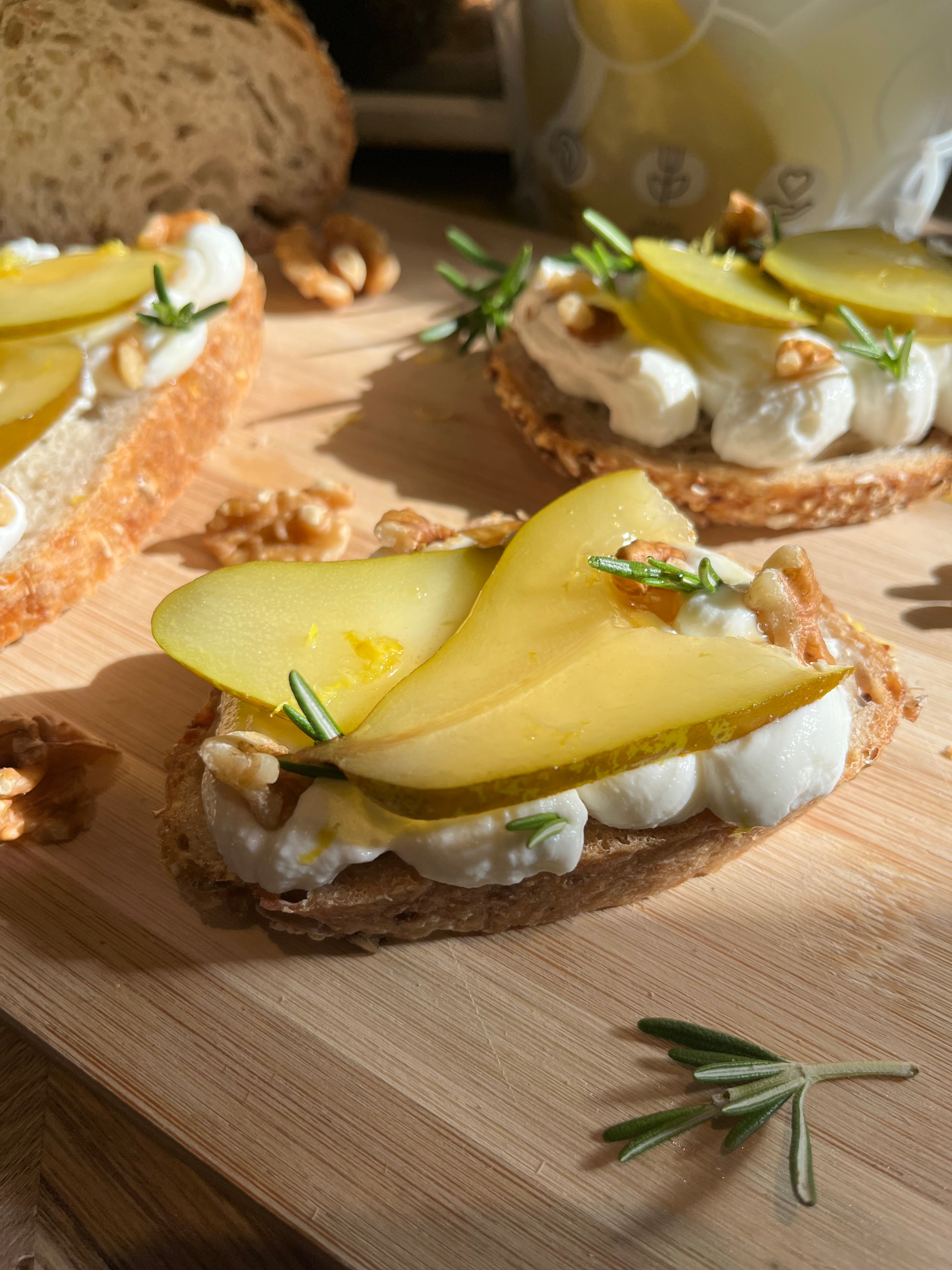 Bread slices with pear and cream cheese on a wooden board