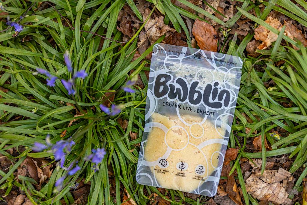 Package of Bwblin organic live ferment on grass with small purple flowers